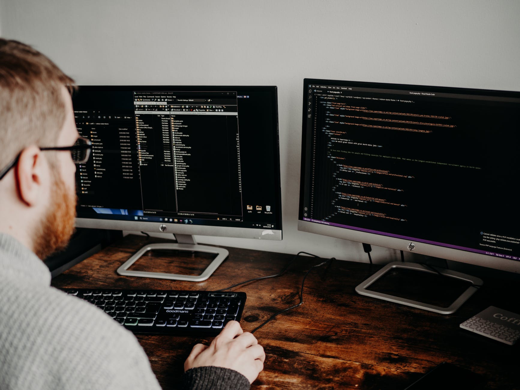 man coding on computers sitting at desk